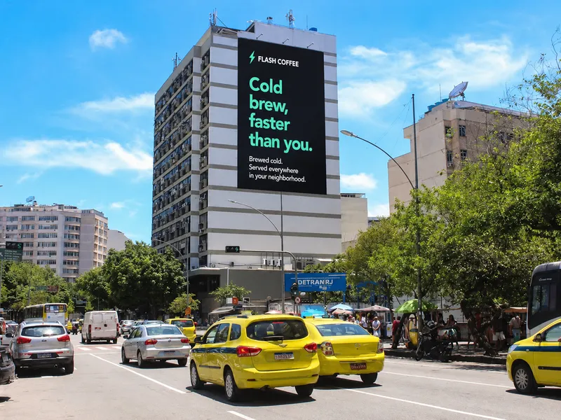 Un grand écran publicitaire sur la façade d'un immeuble au-dessus d'une avenue passante, avec une campagne de cold brew